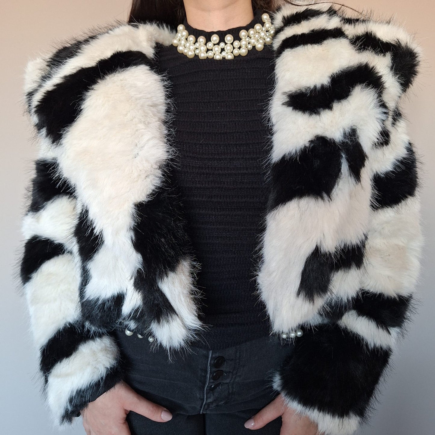 Късо дамско палто Cruella, черно-бяло, с косъм, не се закопчава, с обърната яка, снимано с ръце надолу